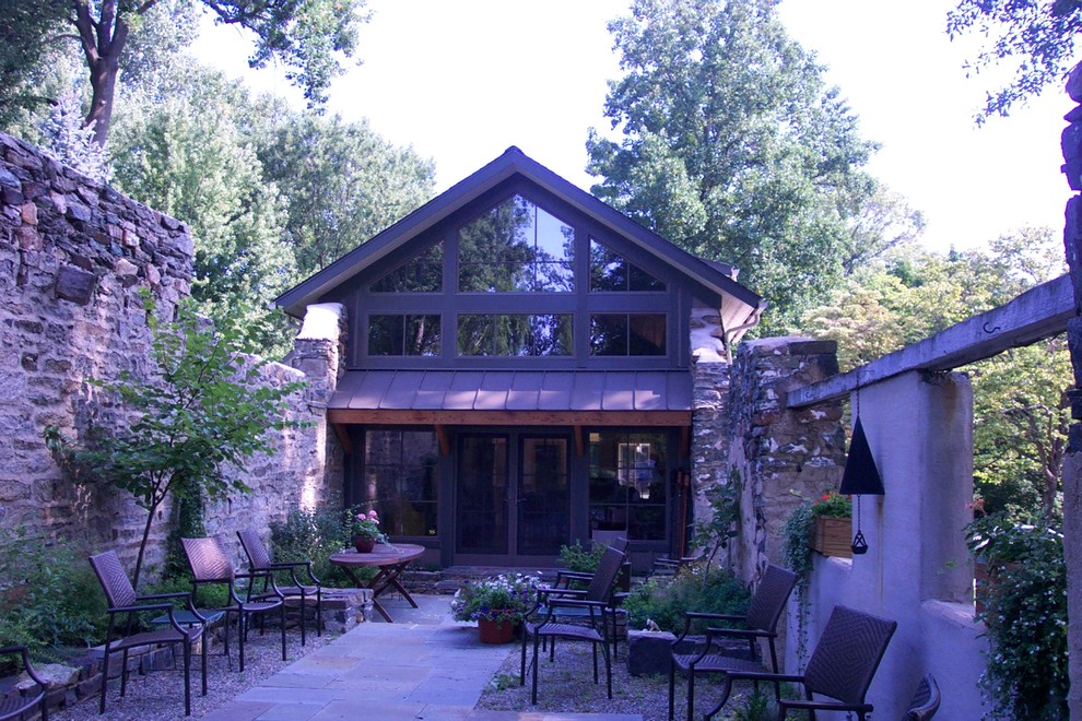 Ejemplo de fachada de casa campestre de tamaño medio de dos plantas con revestimiento de piedra, tejado a dos aguas y tejado de teja de madera