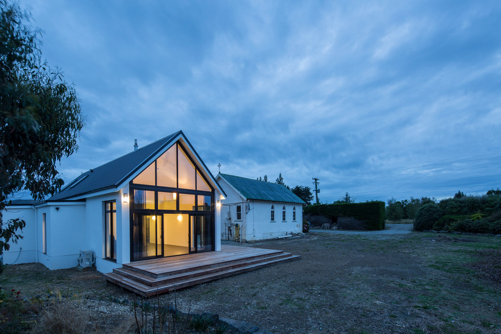 Kleines, Einstöckiges Modernes Haus mit Betonfassade, weißer Fassadenfarbe und Satteldach in Dunedin