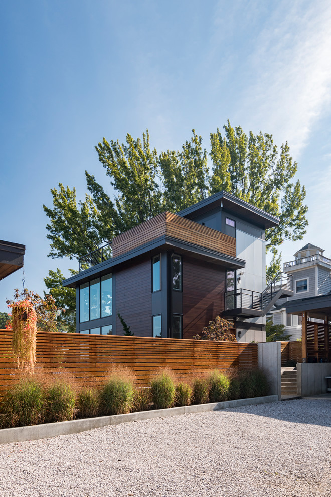 Cette photo montre une petite façade de maison grise moderne en bois à un étage avec un toit plat.