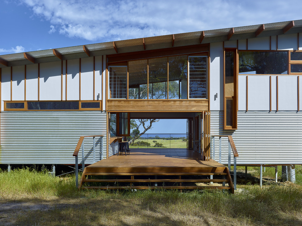 На фото: двухэтажный дом в стиле лофт с облицовкой из металла и односкатной крышей
