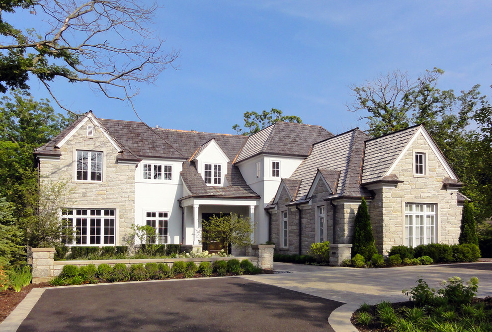 Cette image montre une grande façade de maison blanche traditionnelle en pierre à un étage avec un toit à deux pans.