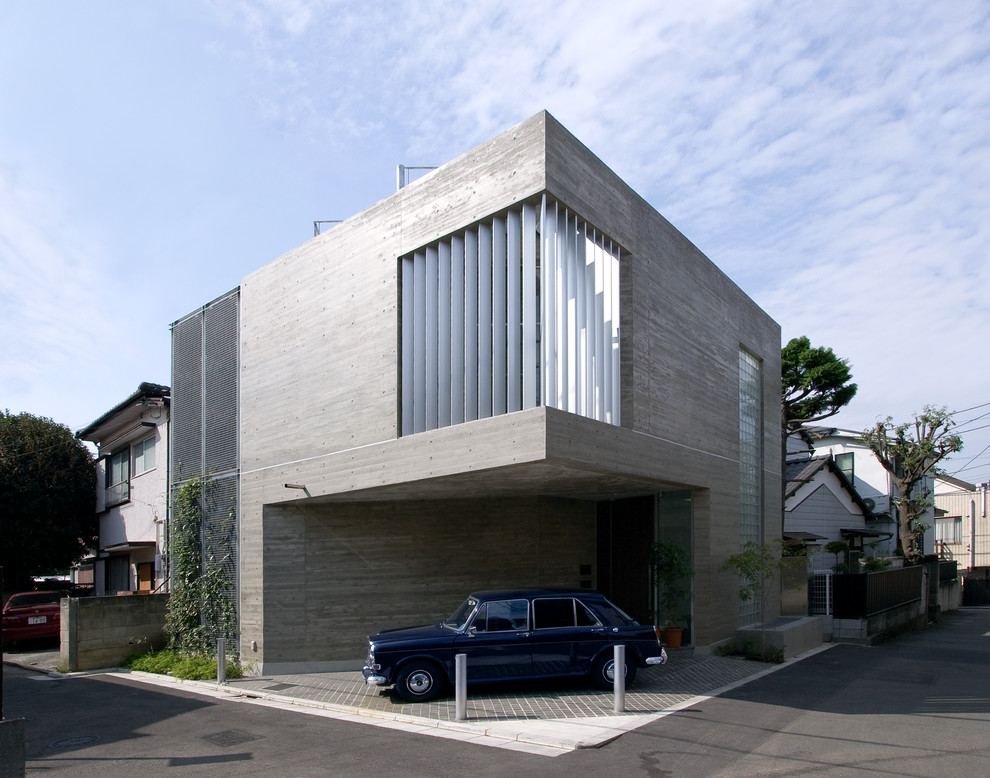 Cette photo montre une façade de maison grise moderne en béton avec un toit plat.
