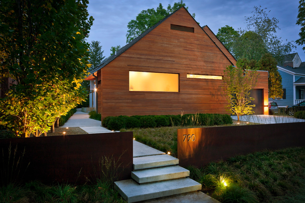 На фото: одноэтажный, деревянный, коричневый частный загородный дом среднего размера в современном стиле с двускатной крышей с