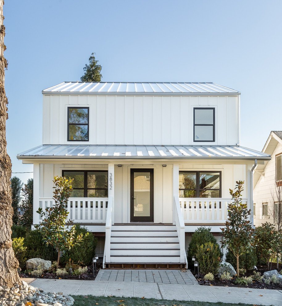 На фото: двухэтажный, белый дом в стиле кантри с облицовкой из металла и двускатной крышей