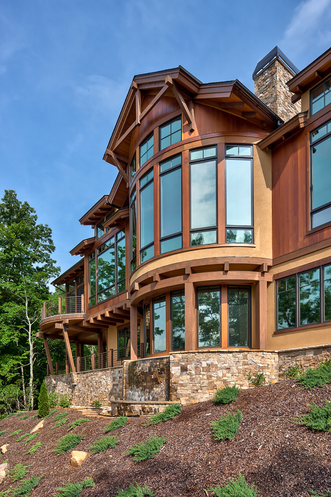 Idée de décoration pour une grande façade de maison marron design en bois à deux étages et plus avec un toit à quatre pans.