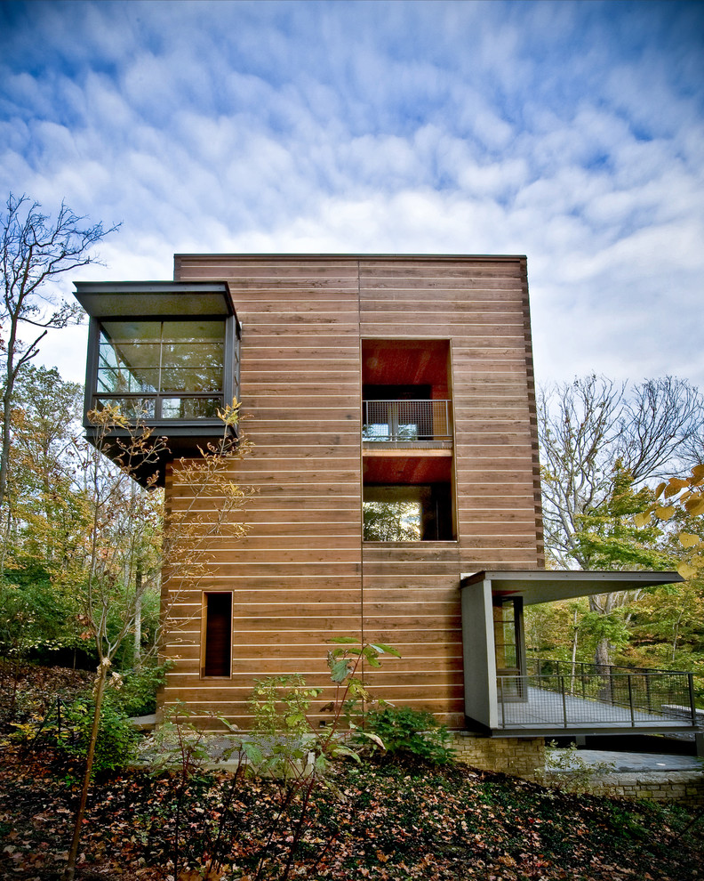 На фото: деревянный, коричневый, трехэтажный, большой частный загородный дом в современном стиле с односкатной крышей и зеленой крышей с