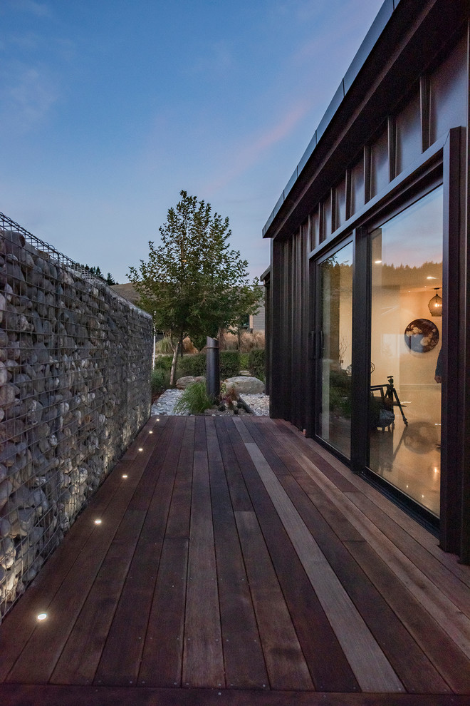 Inspiration pour une grande façade de maison noire minimaliste en bois de plain-pied avec un toit plat et un toit en métal.
