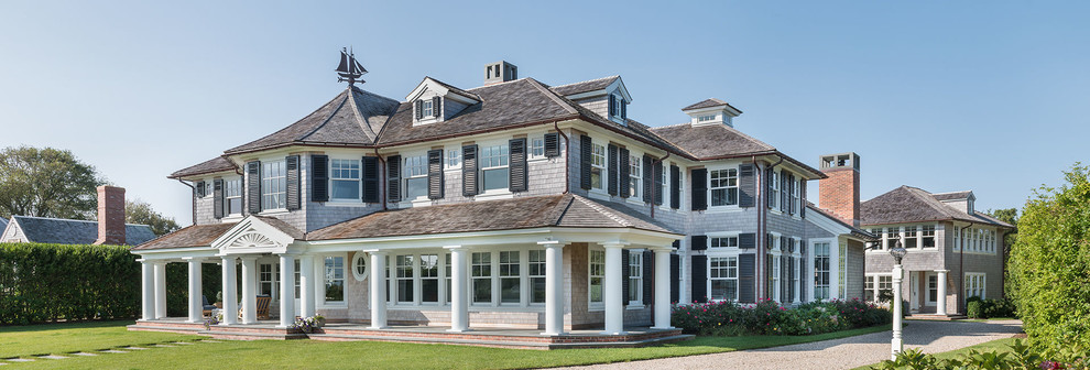 Example of a large beach style gray three-story wood house exterior design in Boston with a shingle roof and a hip roof