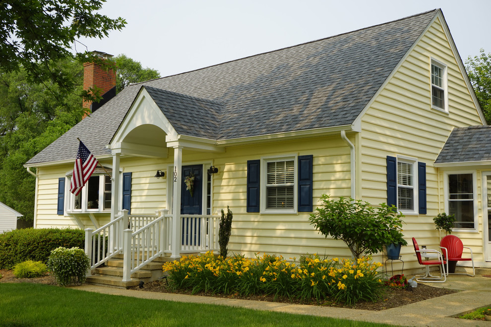 Exempel på ett retro gult hus, med två våningar, vinylfasad och sadeltak