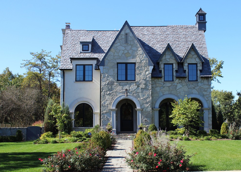 Exemple d'une grande façade de maison beige chic en pierre à un étage avec un toit à deux pans.
