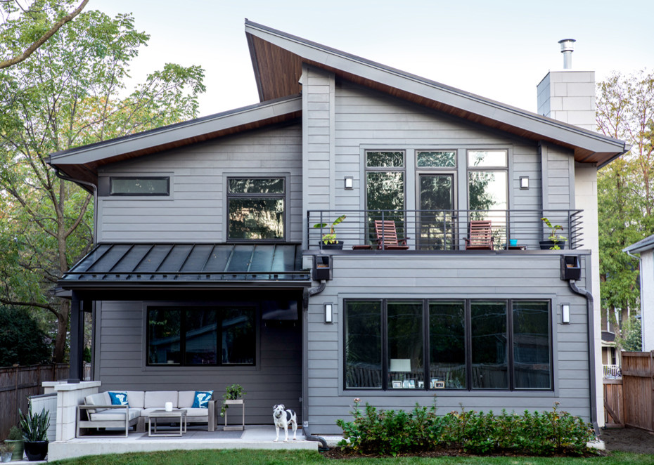 На фото: большой, двухэтажный, серый частный загородный дом в современном стиле с облицовкой из ЦСП, односкатной крышей и металлической крышей с