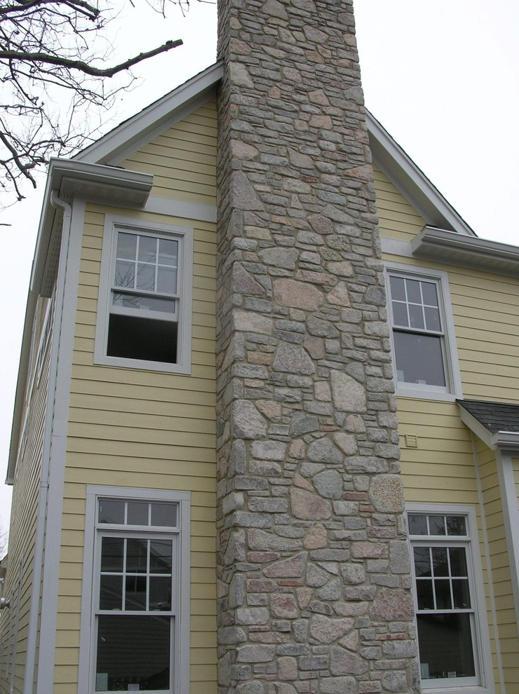 Foto de fachada de casa amarilla clásica de dos plantas con revestimiento de vinilo y tejado de teja de madera