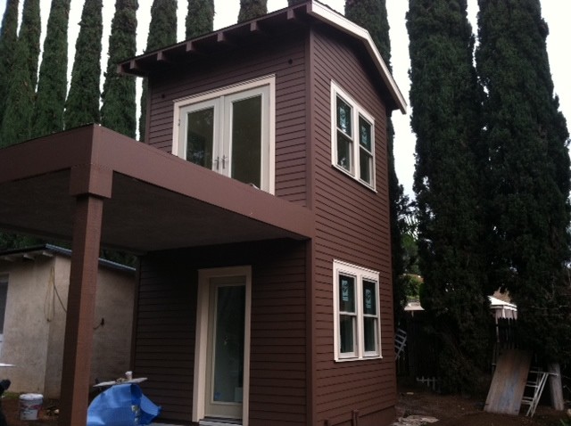 Cette image montre une façade de maison marron minimaliste de taille moyenne et à un étage avec un revêtement mixte et un toit à croupette.