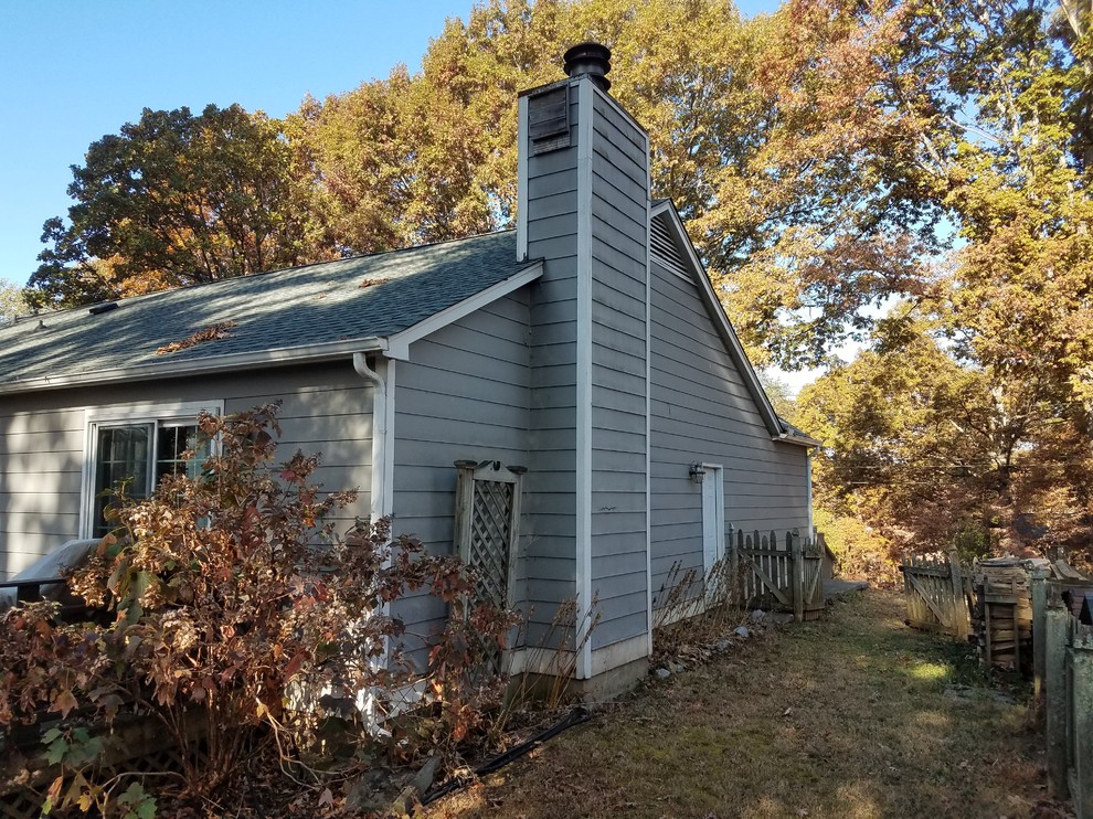 Ejemplo de fachada de casa gris de estilo americano de tamaño medio de una planta con revestimiento de vinilo y tejado de teja de madera