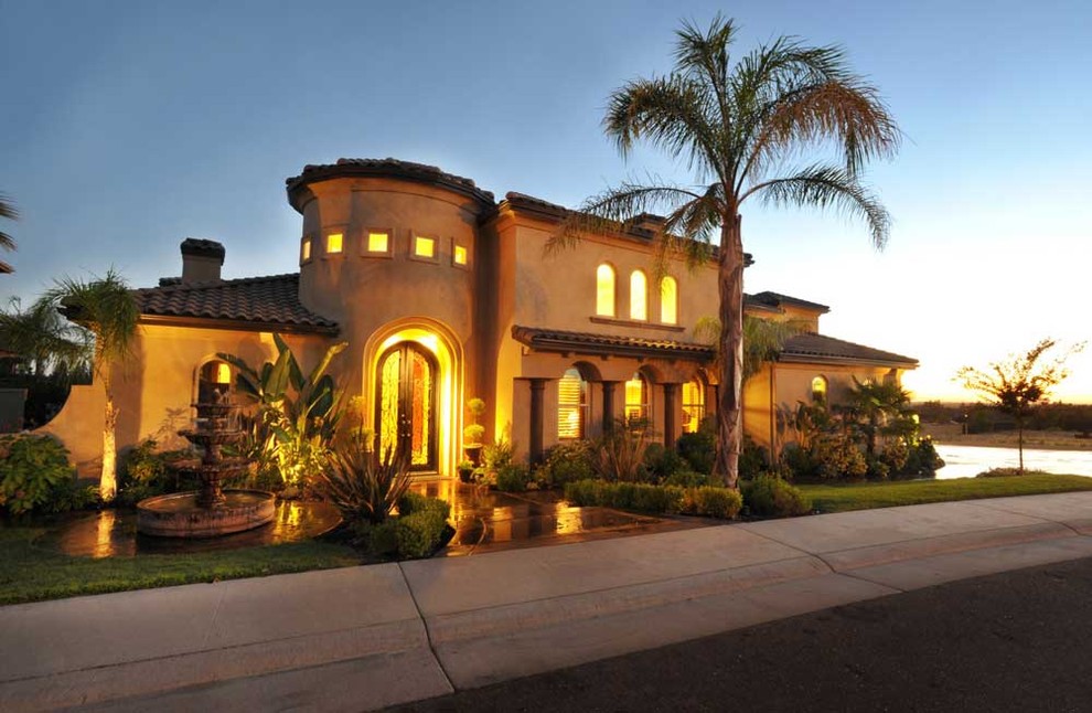 Modelo de fachada de casa beige, mediterránea, grande, de dos plantas, con revestimiento de estuco, tejado a cuatro aguas y tejado de teja de barro