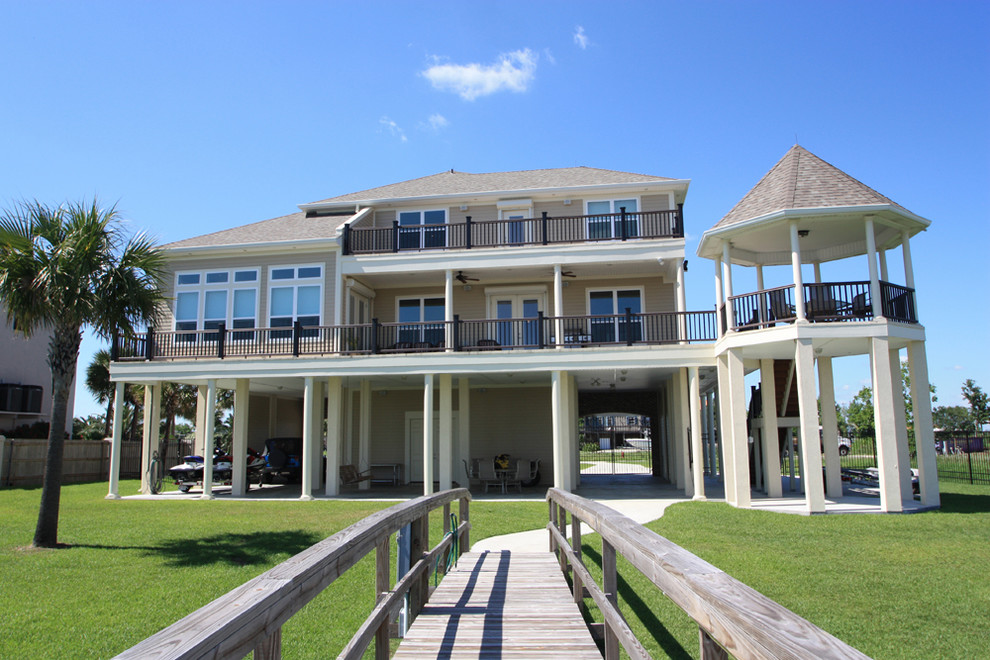Diseño de fachada beige costera grande de tres plantas con revestimientos combinados y tejado a dos aguas