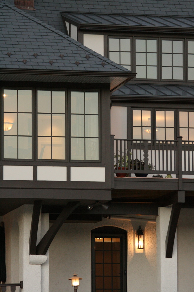 Cette photo montre une grande façade de maison blanche éclectique en stuc à un étage avec un toit à quatre pans.