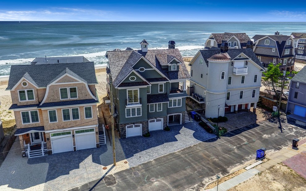 Cette photo montre une grande façade de maison grise bord de mer en bois à deux étages et plus avec un toit à deux pans et un toit en shingle.