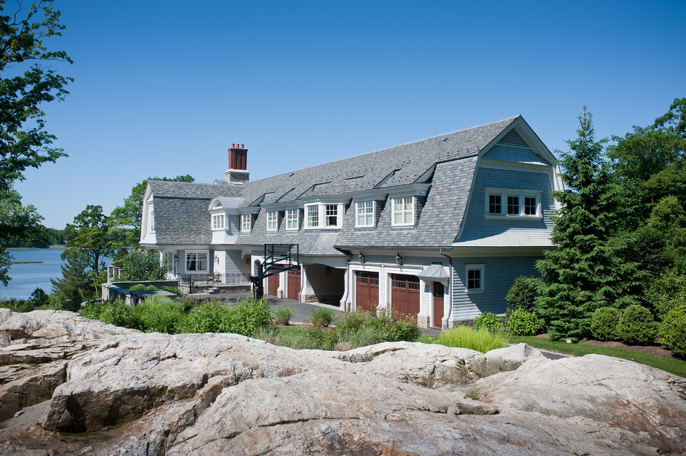 На фото: большой, трехэтажный, деревянный, синий дом в классическом стиле с мансардной крышей с