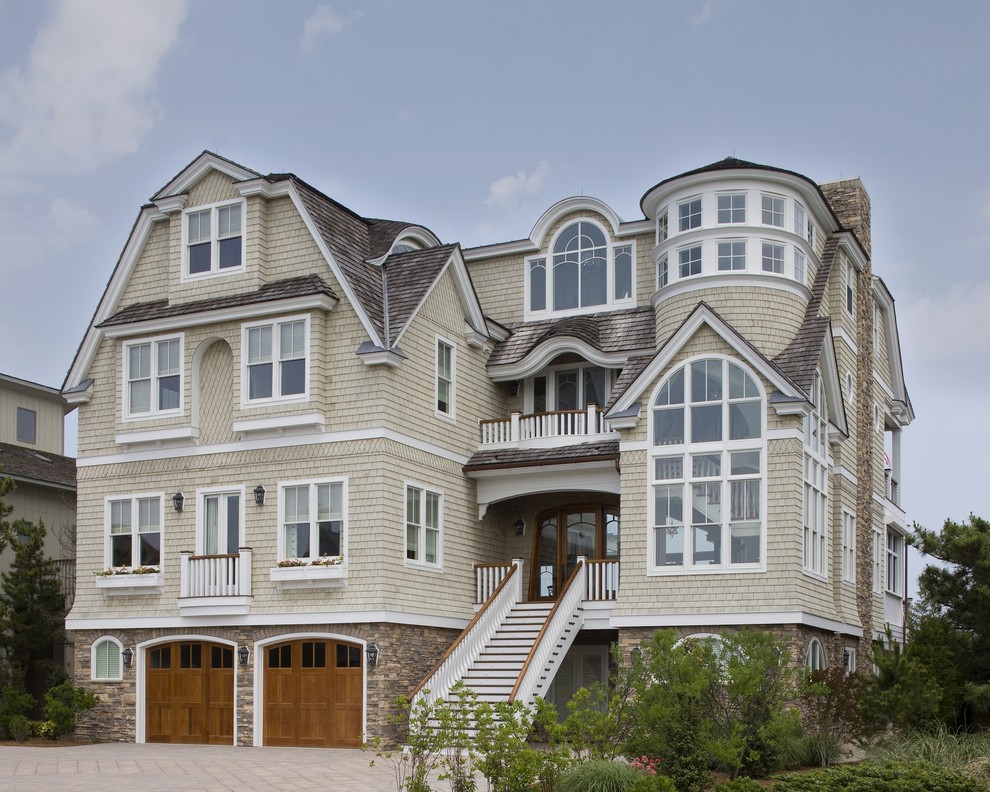 Cette image montre une grande façade de maison beige marine en bois à deux étages et plus.
