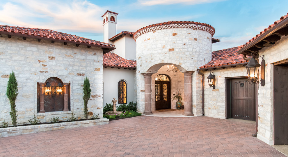 Huge mediterranean beige three-story stone exterior home idea in Austin with a tile roof