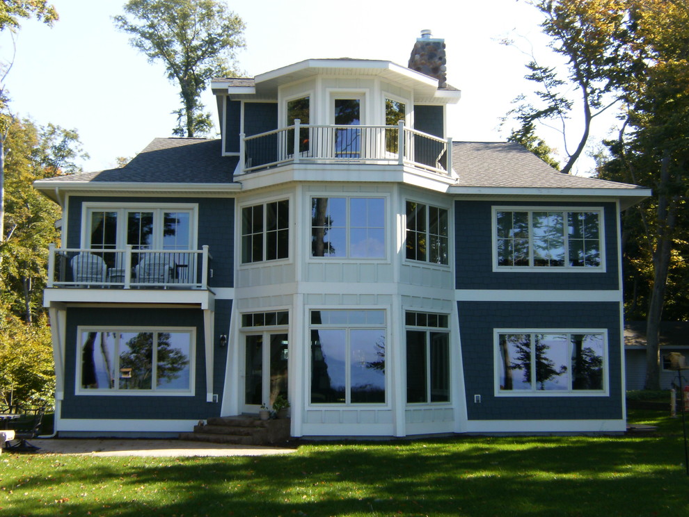 Стильный дизайн: большой, трехэтажный, деревянный, синий частный загородный дом в морском стиле с вальмовой крышей и крышей из гибкой черепицы - последний тренд