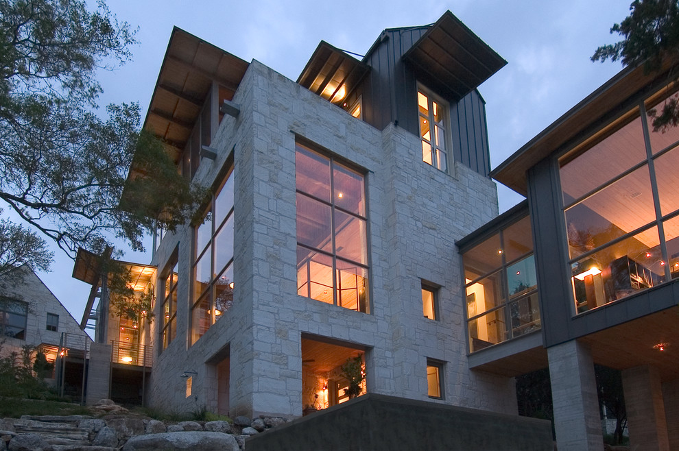 Réalisation d'une grande façade de maison beige design en pierre à deux étages et plus.
