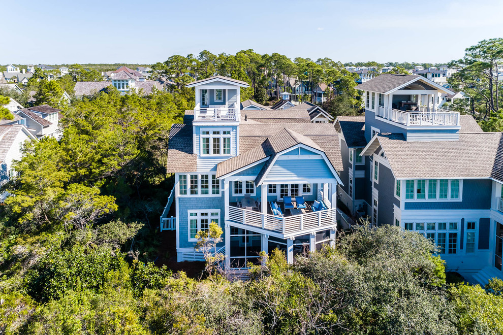 На фото: огромный, трехэтажный, синий частный загородный дом в стиле шебби-шик с крышей из гибкой черепицы