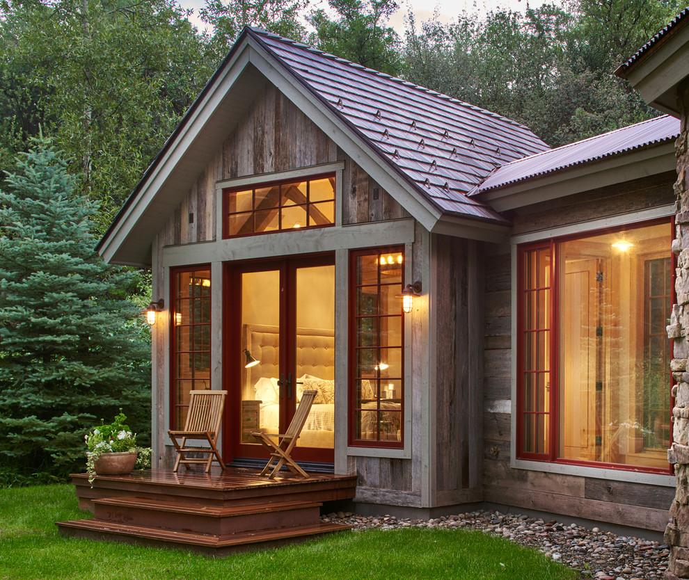 Photo of a rustic bungalow house exterior in Denver with wood cladding and a pitched roof.