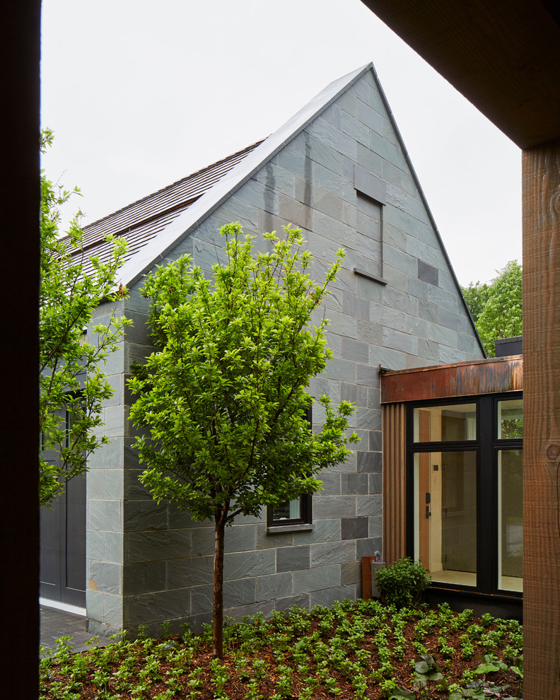 Diseño de fachada gris minimalista de una planta con revestimientos combinados