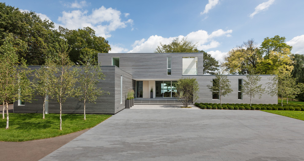 Пример оригинального дизайна: большой, двухэтажный, серый частный загородный дом в стиле модернизм с плоской крышей