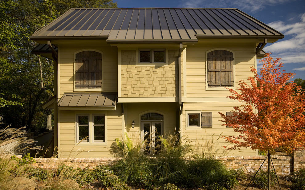 Idee per la facciata di una casa beige american style a tre piani di medie dimensioni con rivestimento con lastre in cemento e tetto a capanna