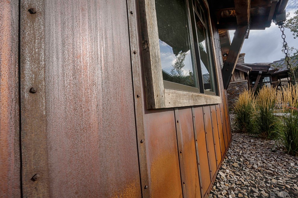 На фото: коричневый частный загородный дом в стиле рустика с облицовкой из металла и металлической крышей с