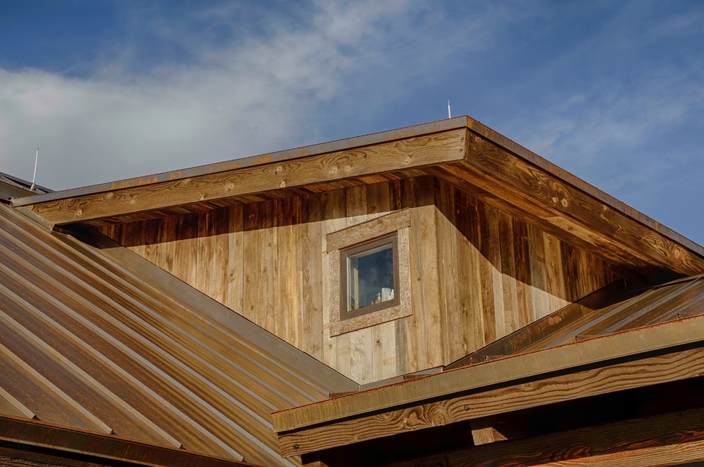Aménagement d'une façade de maison montagne en bois avec un toit mixte.
