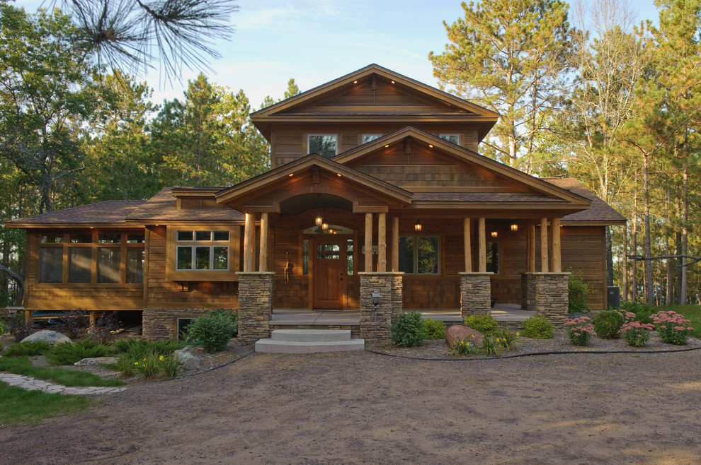 Пример оригинального дизайна: двухэтажный, деревянный, коричневый частный загородный дом в стиле рустика с двускатной крышей и крышей из гибкой черепицы