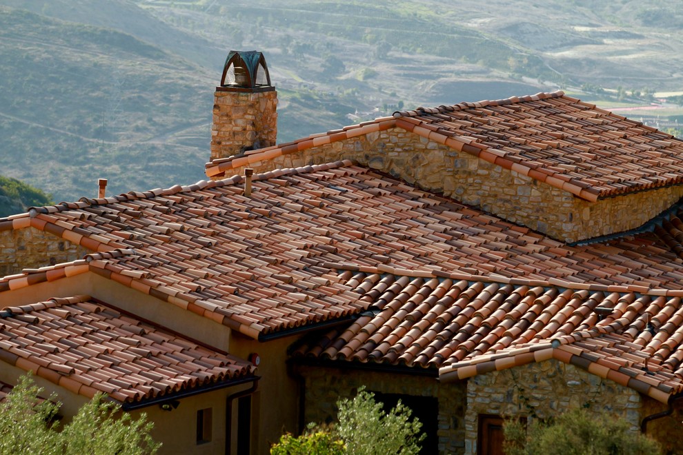 Immagine della facciata di una casa grande marrone mediterranea a un piano con rivestimento in pietra
