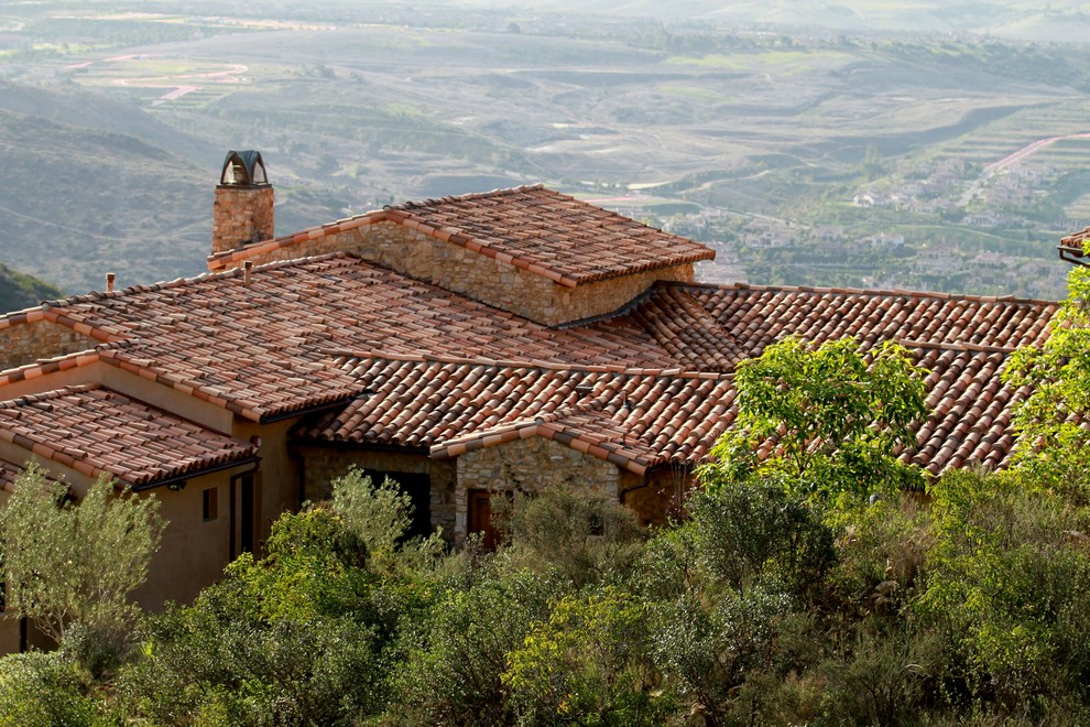 Foto della facciata di una casa grande marrone mediterranea a un piano con rivestimento in pietra