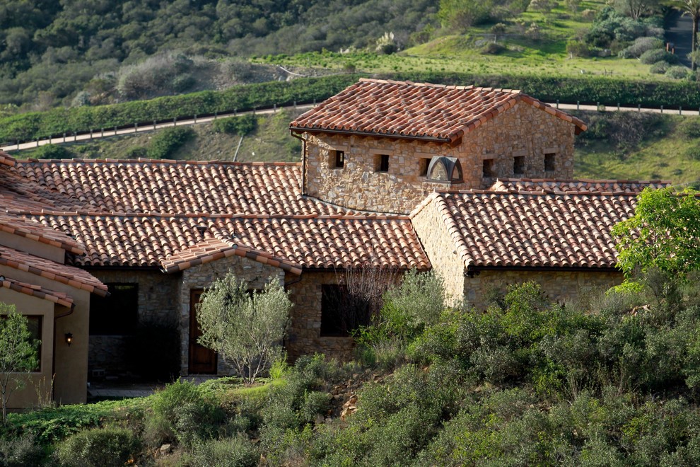 Imagen de fachada marrón mediterránea grande de una planta con revestimiento de piedra