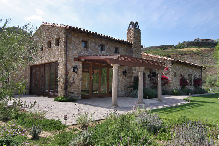 Idée de décoration pour une grande façade de maison marron méditerranéenne en pierre de plain-pied.