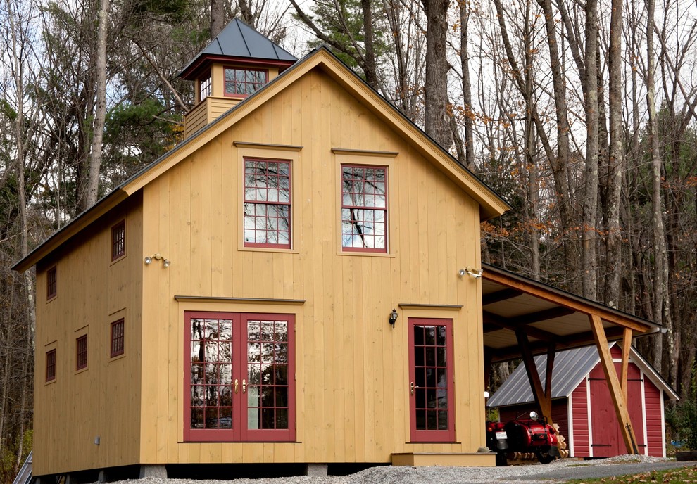 Immagine della facciata di una casa country a due piani con rivestimento in legno