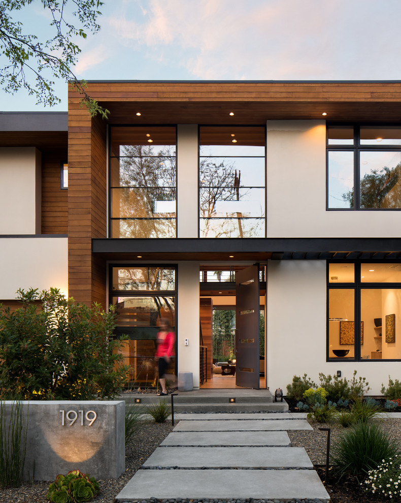 Imagen de fachada de casa contemporánea de dos plantas con revestimientos combinados y tejado plano
