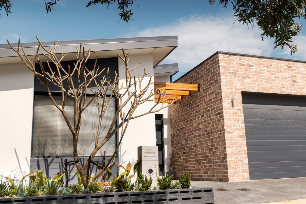 Esempio della villa multicolore contemporanea a un piano di medie dimensioni con rivestimento in mattoni, tetto piano e copertura in metallo o lamiera