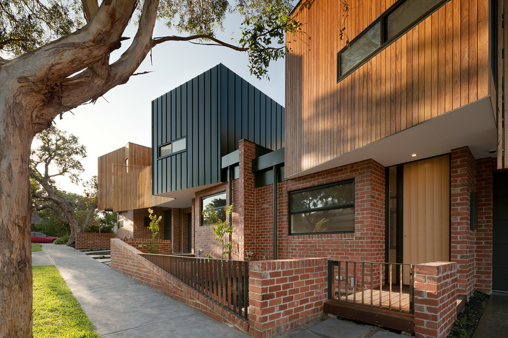 Cette photo montre une façade de maison marron tendance en bois de taille moyenne et à un étage avec un toit plat.
