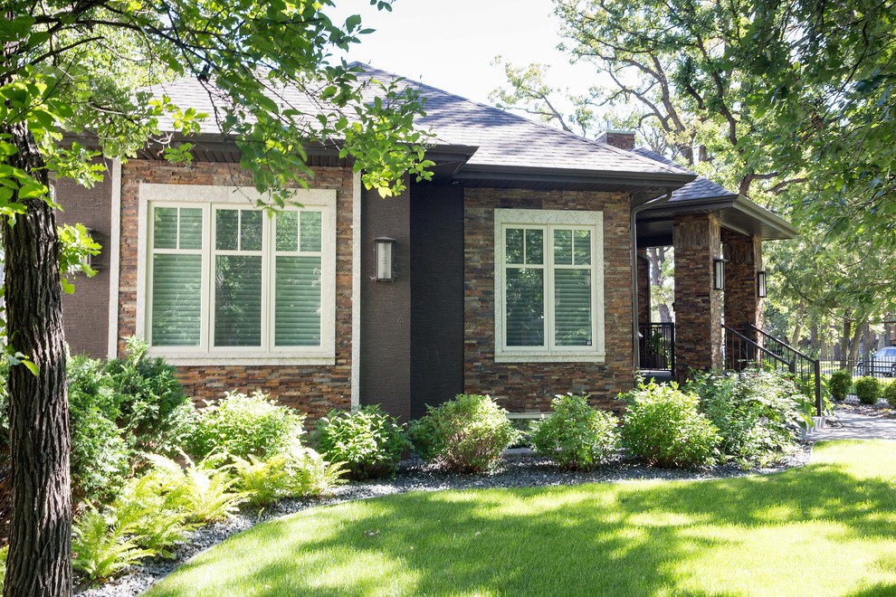 Example of a large trendy brown one-story stone house exterior design in Other with a hip roof and a shingle roof
