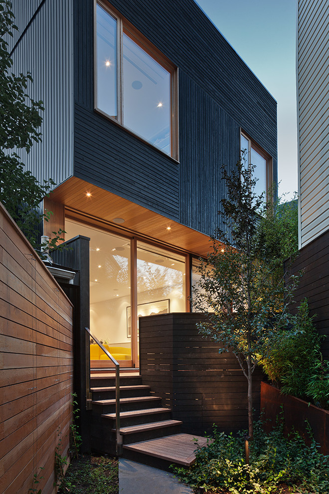 Medium sized and black modern house exterior in Toronto with three floors and wood cladding.