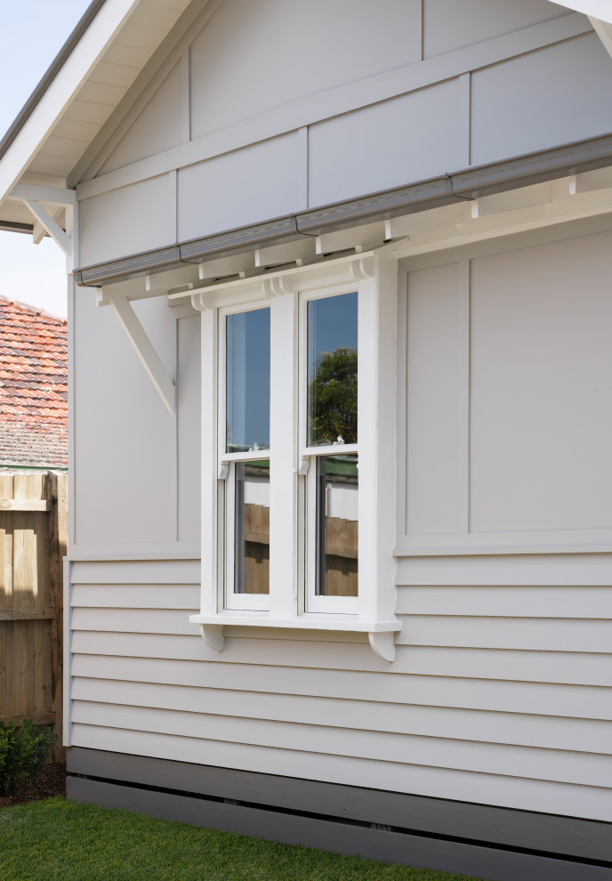 Cette image montre une façade de maison blanche design en bois de taille moyenne et à un étage avec un toit en métal et un toit à deux pans.