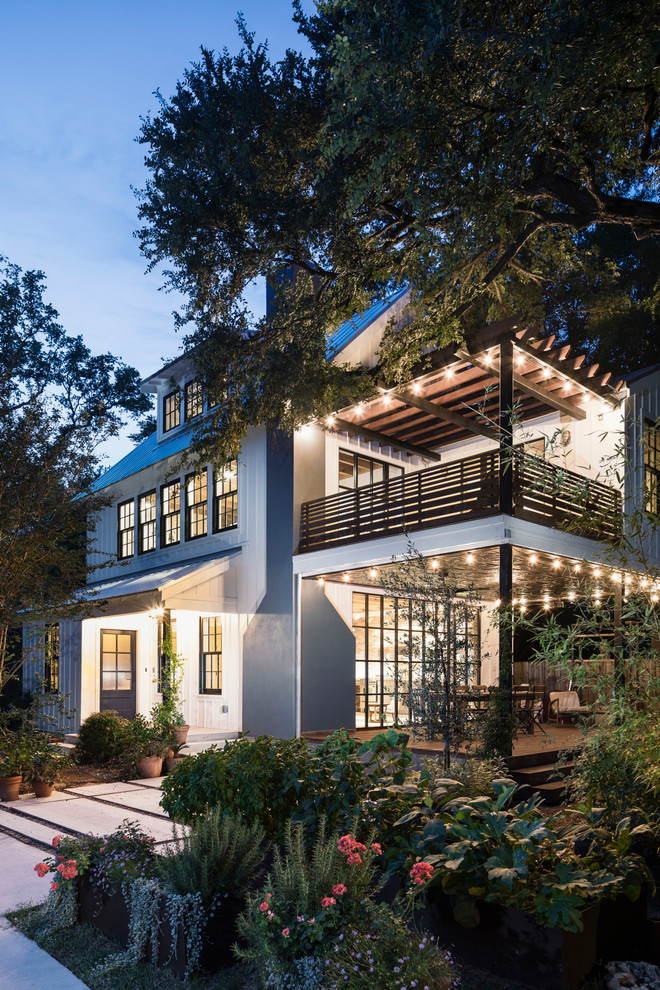 Mittelgroßes, Dreistöckiges Landhausstil Haus mit weißer Fassadenfarbe, Satteldach und Blechdach in Austin