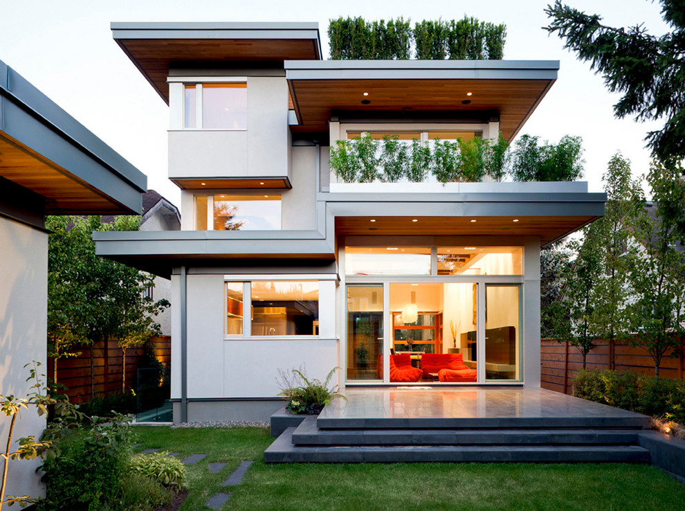 Пример оригинального дизайна: трехэтажный, серый дом в современном стиле с облицовкой из цементной штукатурки и плоской крышей