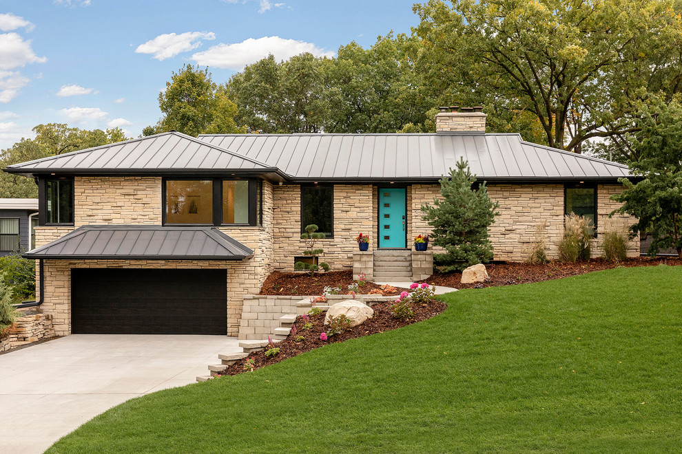Diseño de fachada de casa beige actual de tamaño medio con revestimiento de piedra, tejado a cuatro aguas y tejado de metal