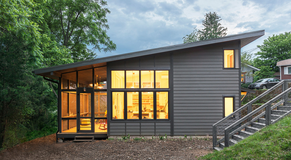 На фото: маленький, двухэтажный, деревянный, серый частный загородный дом в стиле модернизм с плоской крышей и металлической крышей для на участке и в саду